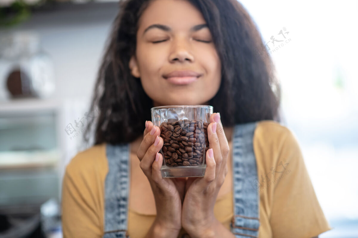 女人振作能源玻璃一个闭着眼睛的女人手里拿着香喷喷的咖啡豆咖啡豆吸入器享受