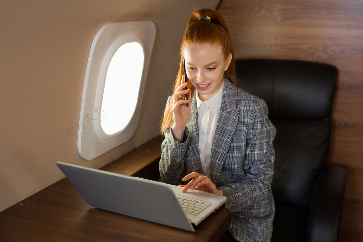 飞机一位红发美女在机舱里拿着笔记本电脑用户飞机在线