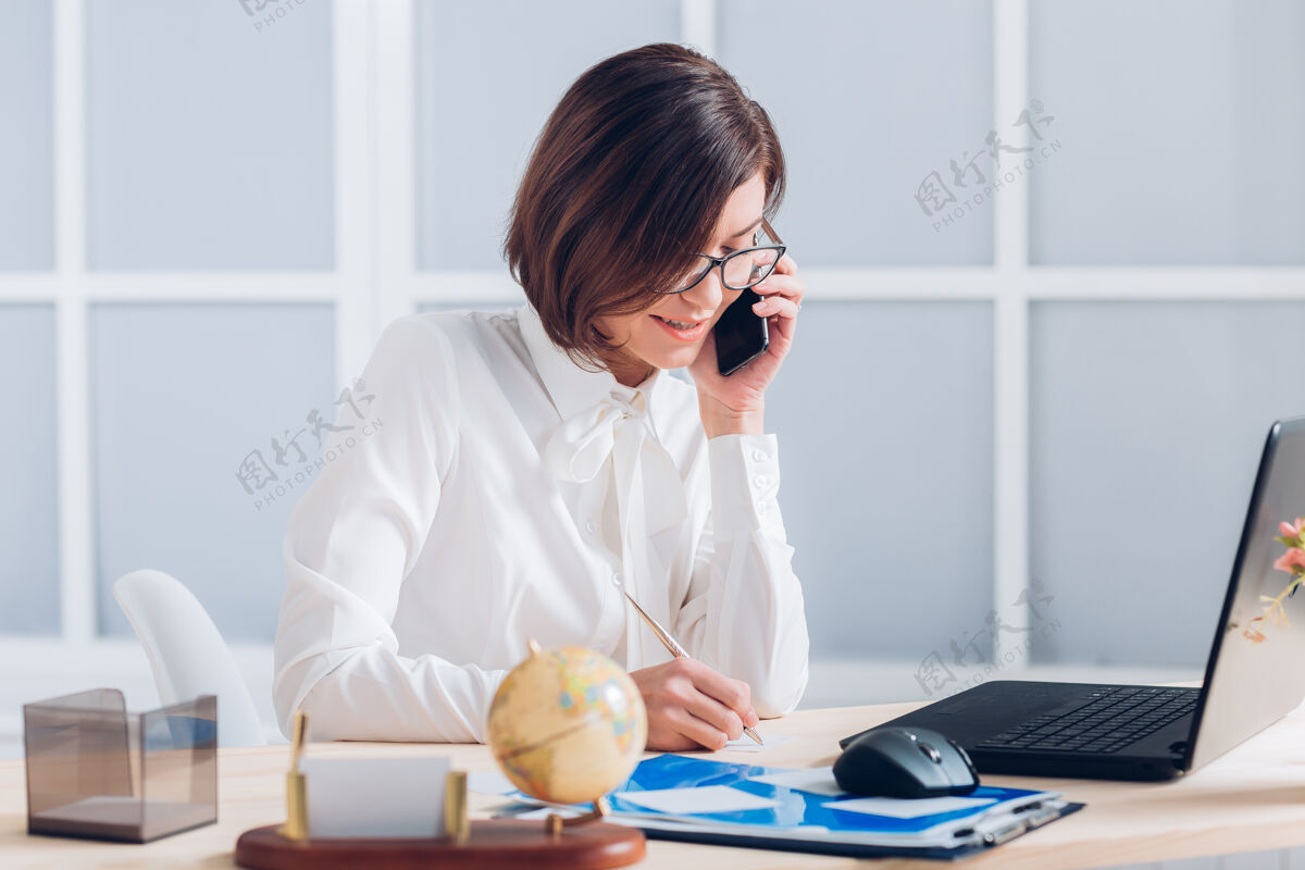 成功漂亮的女商人在办公室打电话和办公桌边工作企业工作场所快乐