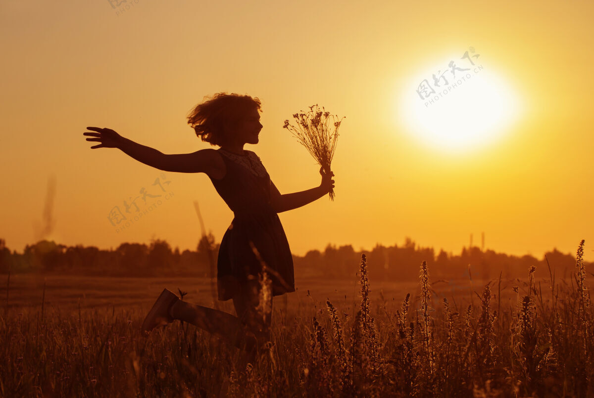 牛仔裤美丽的少女在夏天的田野与矢车菊风景花束乡村