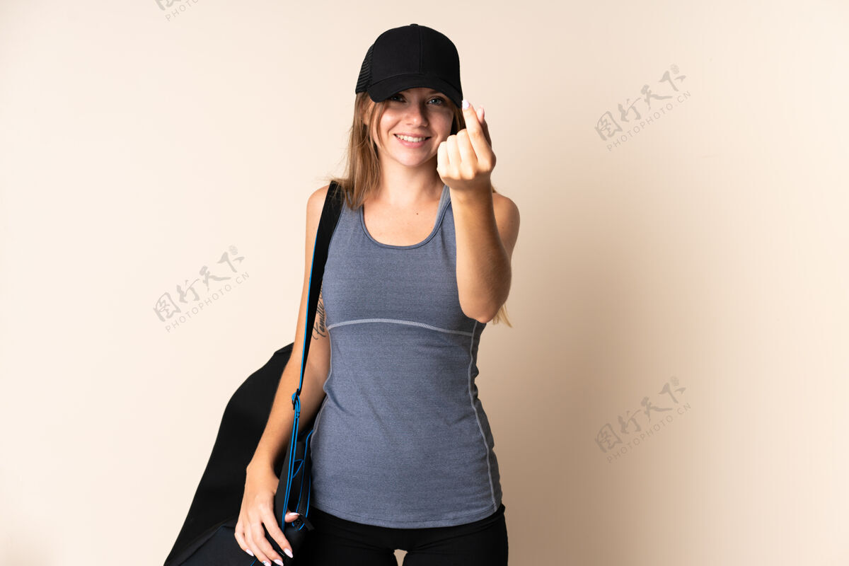好年轻的运动立陶宛女子拿着一个运动袋孤立在米色背景做即将到来的姿态女孩关心期待