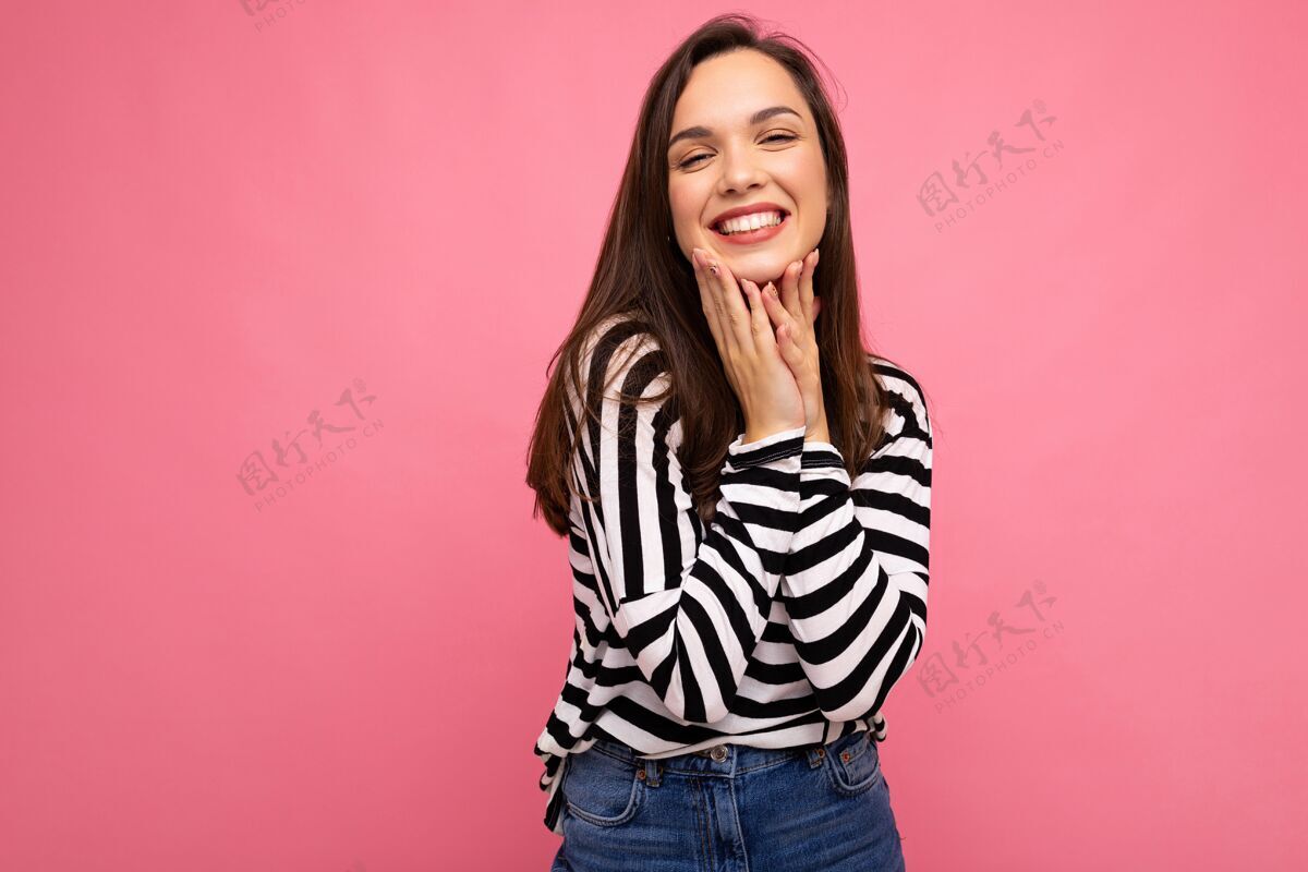 女性照片中的年轻微笑积极快乐美丽的深肤色女性 带着真诚的情感 穿着休闲条纹套头衫 粉色背景上有复制空间黑白时髦漂亮