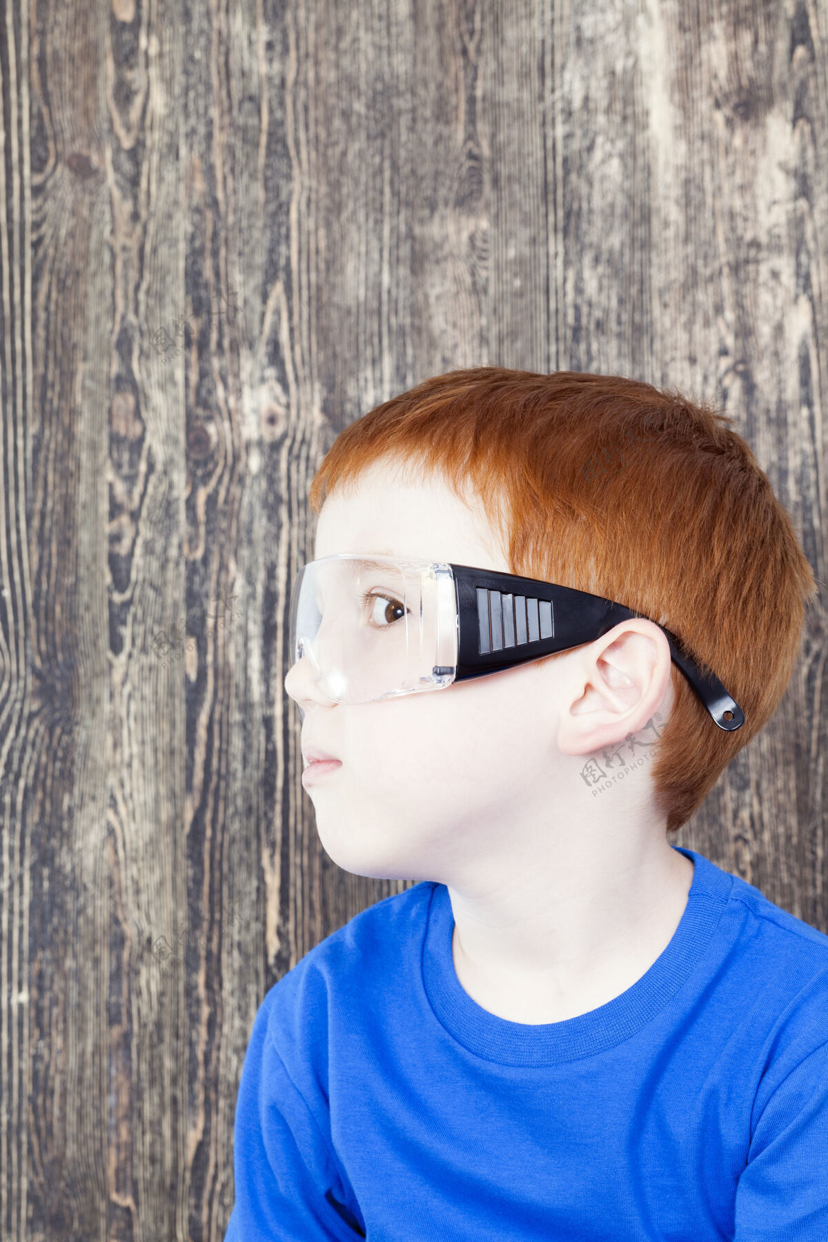 建筑商一头红发的欧洲男孩 头戴透明护目镜 一边玩建筑工人幼儿园小游戏