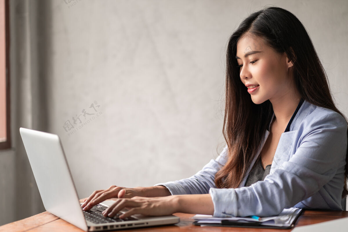 生活方式年轻快乐的亚洲女商人 穿着蓝色衬衫 在家工作 使用笔记本电脑 为自己的事业思考笔记本自由职业者精益
