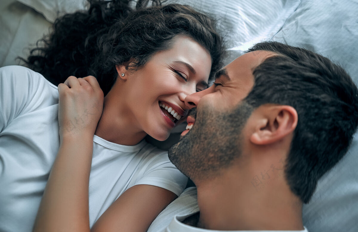 微笑美丽的情侣在床上接吻在一起房间性