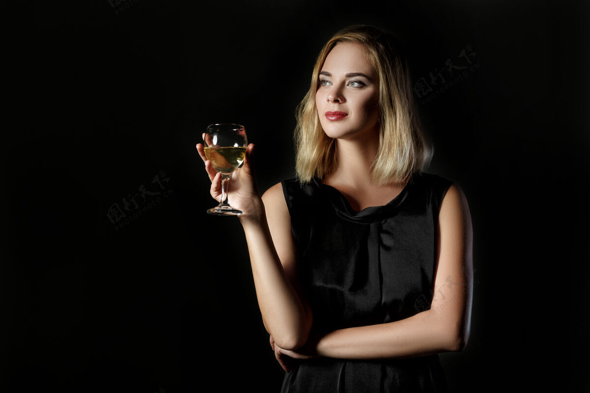 时尚美丽的金发女人 一杯黑底白葡萄酒年女性女人