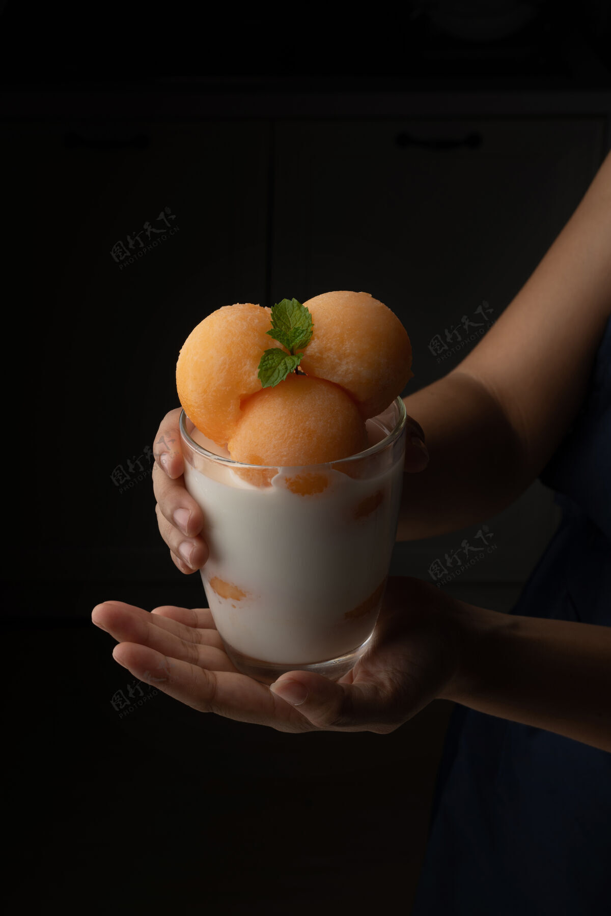 手黄瓜瓜被舀成一个圆球状 像冰淇淋一样放进一个透明的杯子里 上面放着鲜奶 香甜可口好吃吃吧黑色背景上的照片切片甜瓜甜
