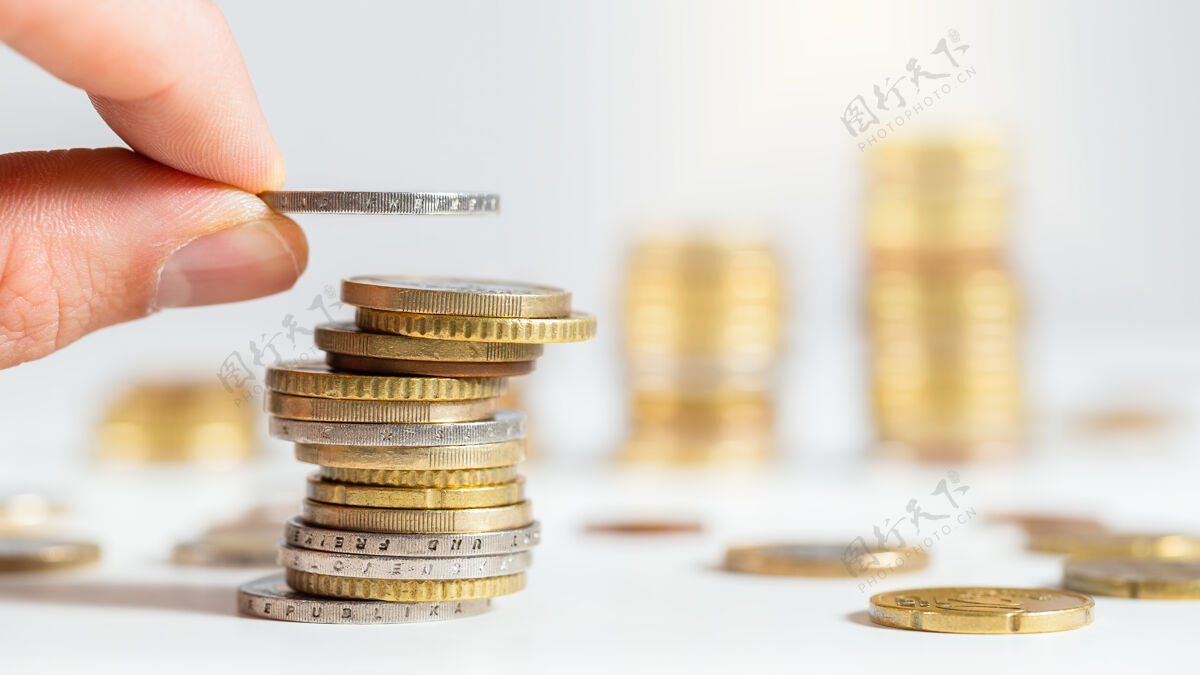 人在一堆欧元上手工添加一枚硬币 其他硬币堆在背景中堆放硬币添加