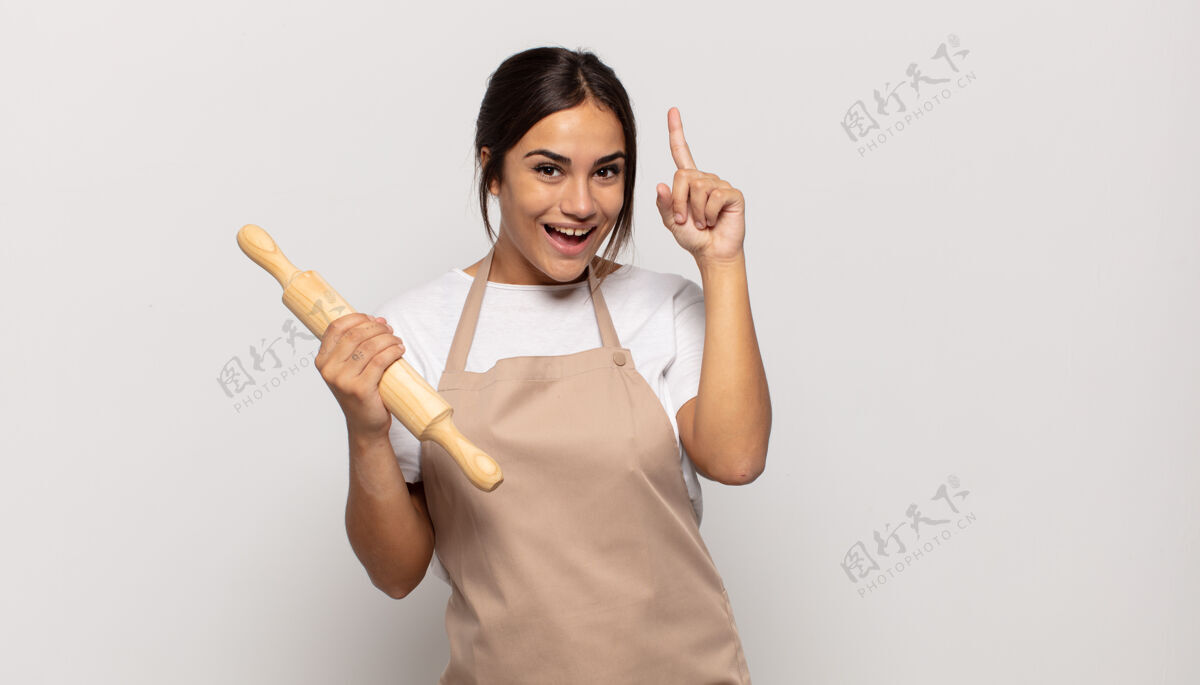 表情年轻的西班牙裔妇女在意识到一个想法后 感觉自己像一个快乐和兴奋的天才 高兴地举起手指 尤里卡烹饪烘焙可爱