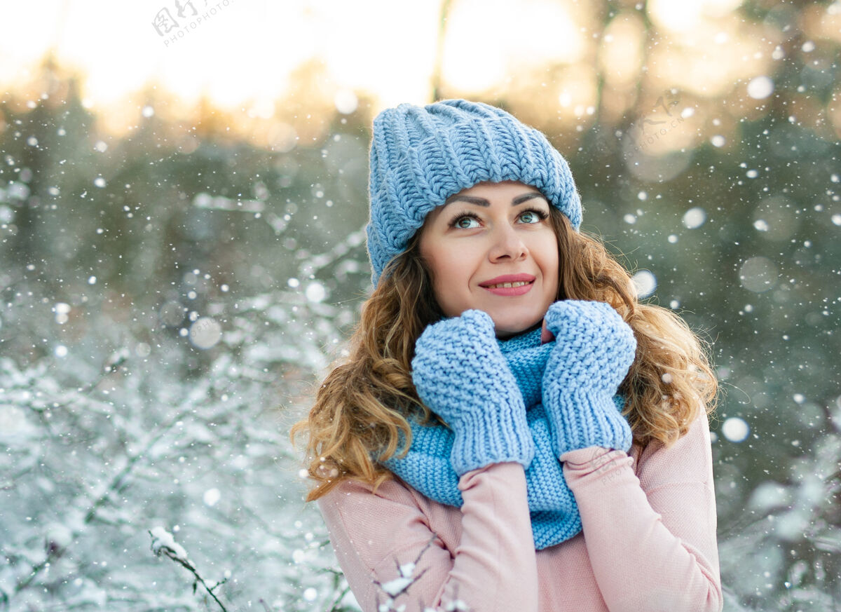 帽子冬天的肖像画 年轻漂亮的卷发黑发女子戴着蓝色针织围巾覆盖在雪上冬天的衣服户外成人