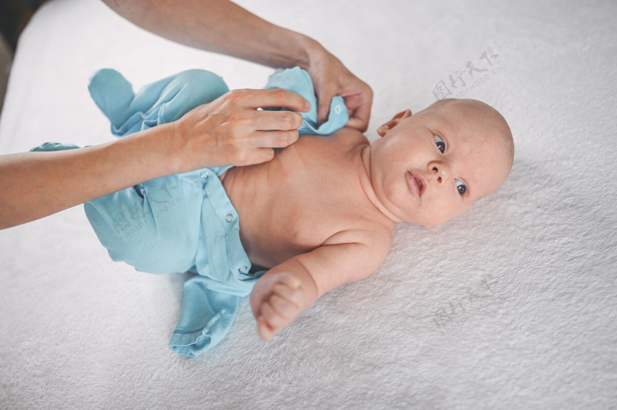 美丽妈妈穿着可爱的情绪有趣的新生小男婴在蓝色连体衣改变孩子医院