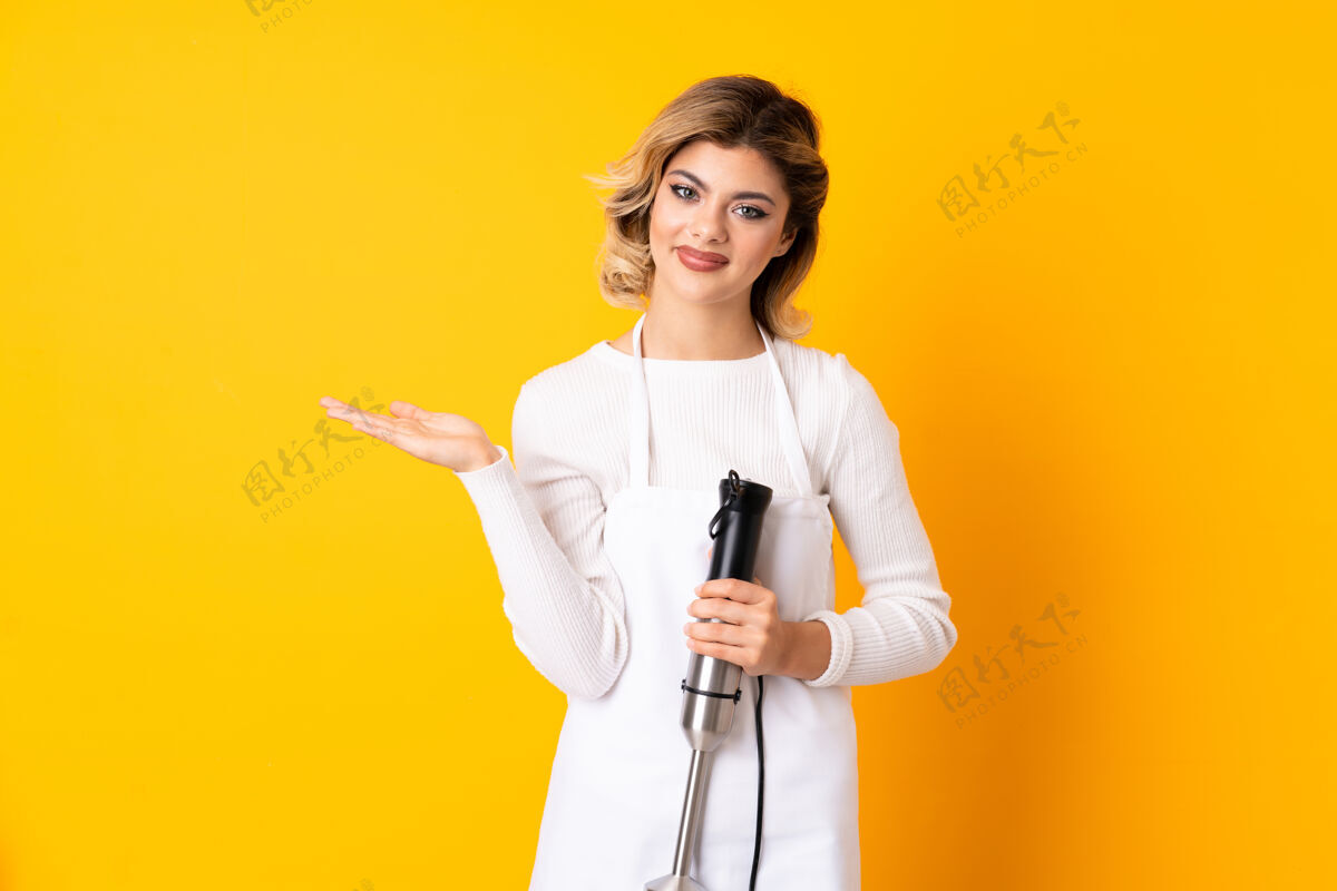 空女孩用手摇搅拌机隔离在黄色的手掌上拿着想象中的文字空间插入广告混合混合饮料