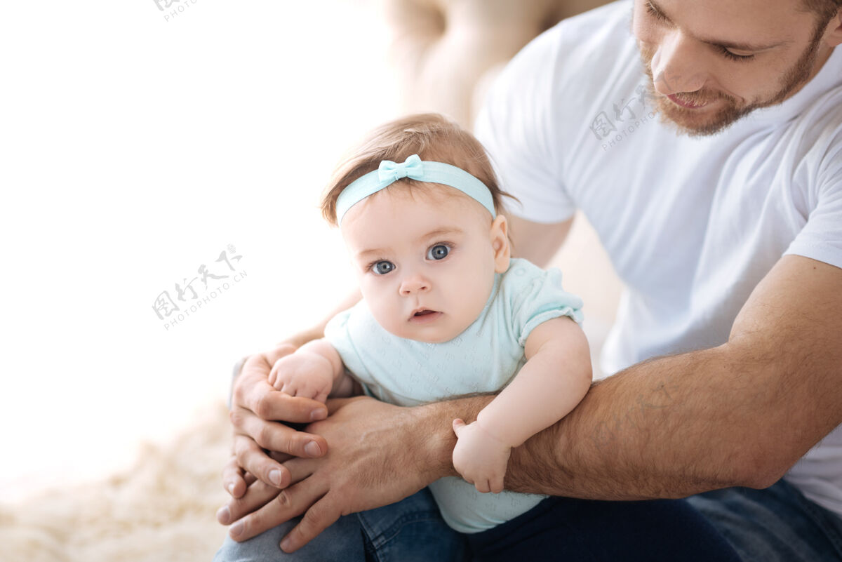 后代发现新的奇怪的事可爱的小女孩躺在年轻的父亲手里 一边看一边表示兴趣爱世代幼儿