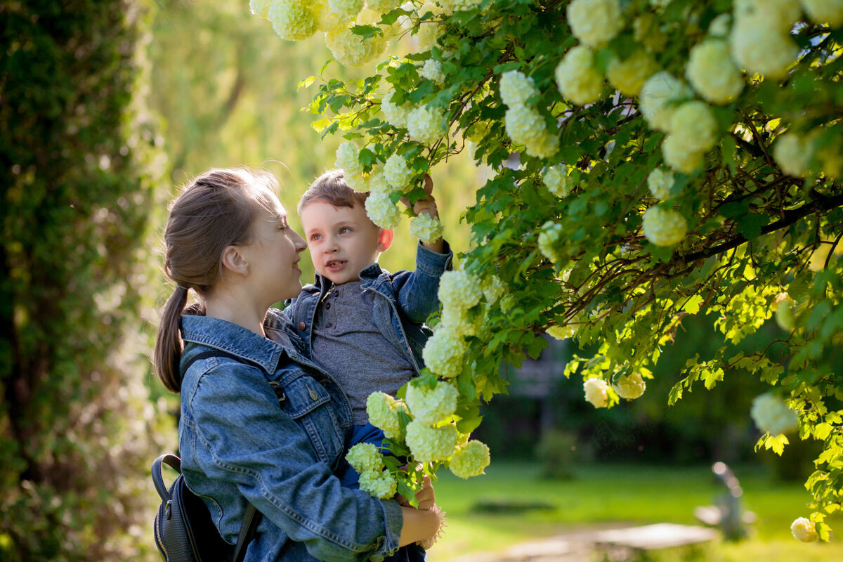 男性在温暖的春天或夏天 快乐的年轻母亲和她的小儿子在公园里玩耍和玩耍孩子草家庭