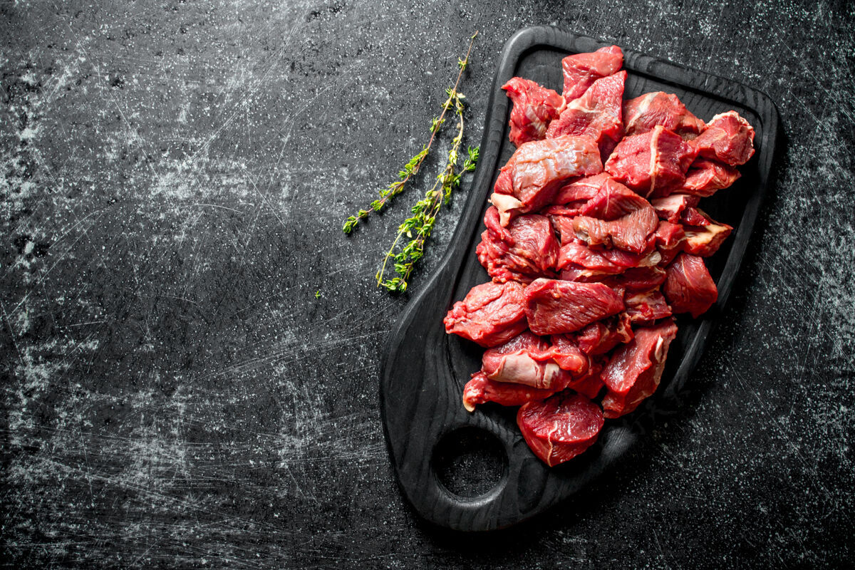 牛肉把生牛肉片放在黑砧板上 配上百里香营养生的餐