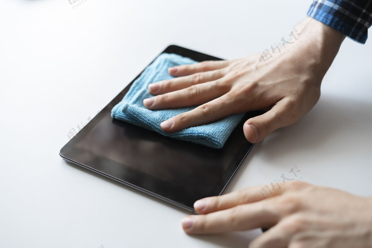 家庭一只手拿着一块抹布 擦拭着一个数码监控屏幕的装置保护家务人
