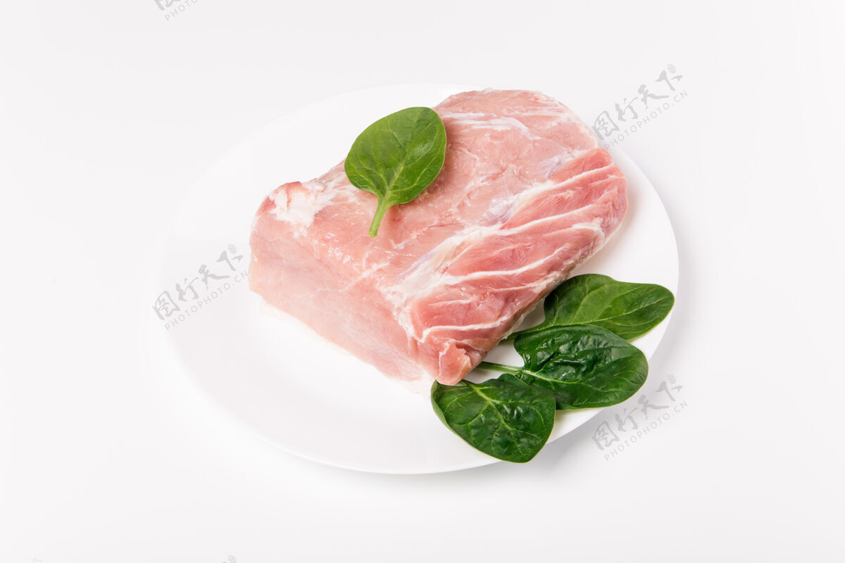 新鲜一块生猪肉和菠菜放在白色陶瓷上板.整体复制空间上的一块肉收集营养生的