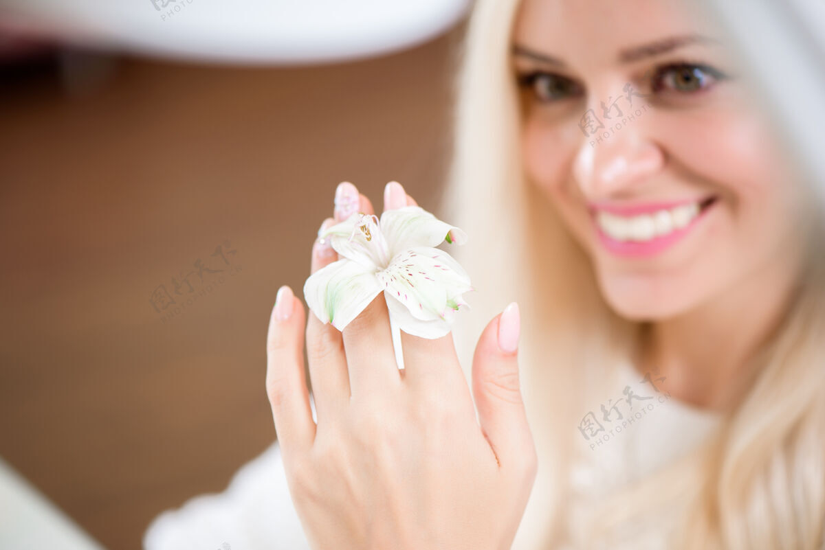 指甲美丽娇嫩的手拿着修指甲的百合花女性帮宝适化妆品