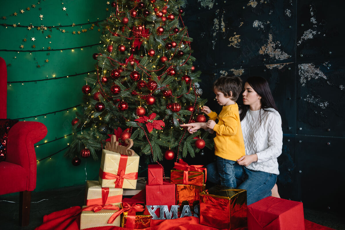 妈妈年轻美丽的母亲带着可爱的儿子在圣诞树旁礼物快乐圣诞节快乐圣诞圣诞树