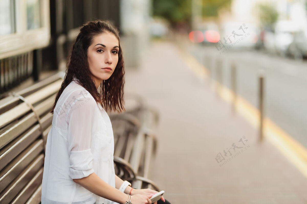 人年轻漂亮的女人在车站等公共汽车停高高质量的照片坐着户外无忧无虑
