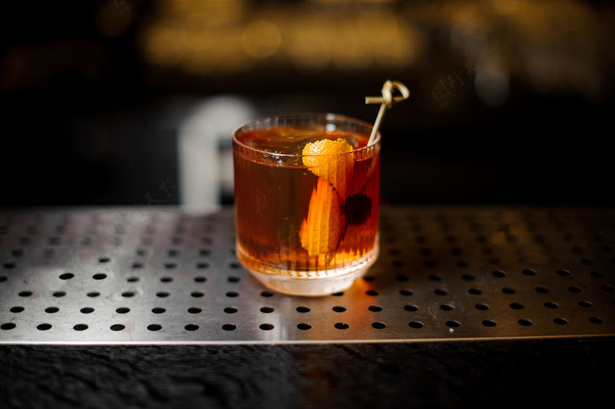 利口酒吧台上摆着一杯用橘皮和樱桃装饰的威士忌鸡尾酒配料玻璃苏格兰