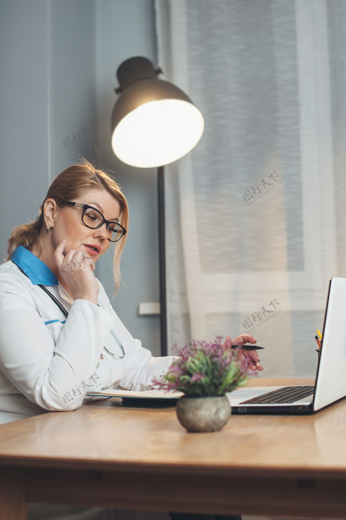 在线在家工作的高级医生正在使用笔记本电脑和穿着医疗服和工具与患者进行在线会议年轻人住宅互联网