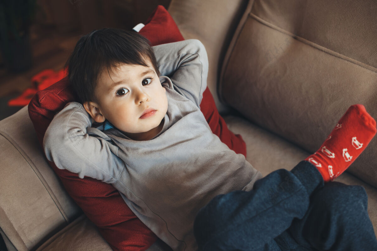 感染上图：隔离期间 一个白人男孩躺在沙发上仰望镜头情绪流行婴儿