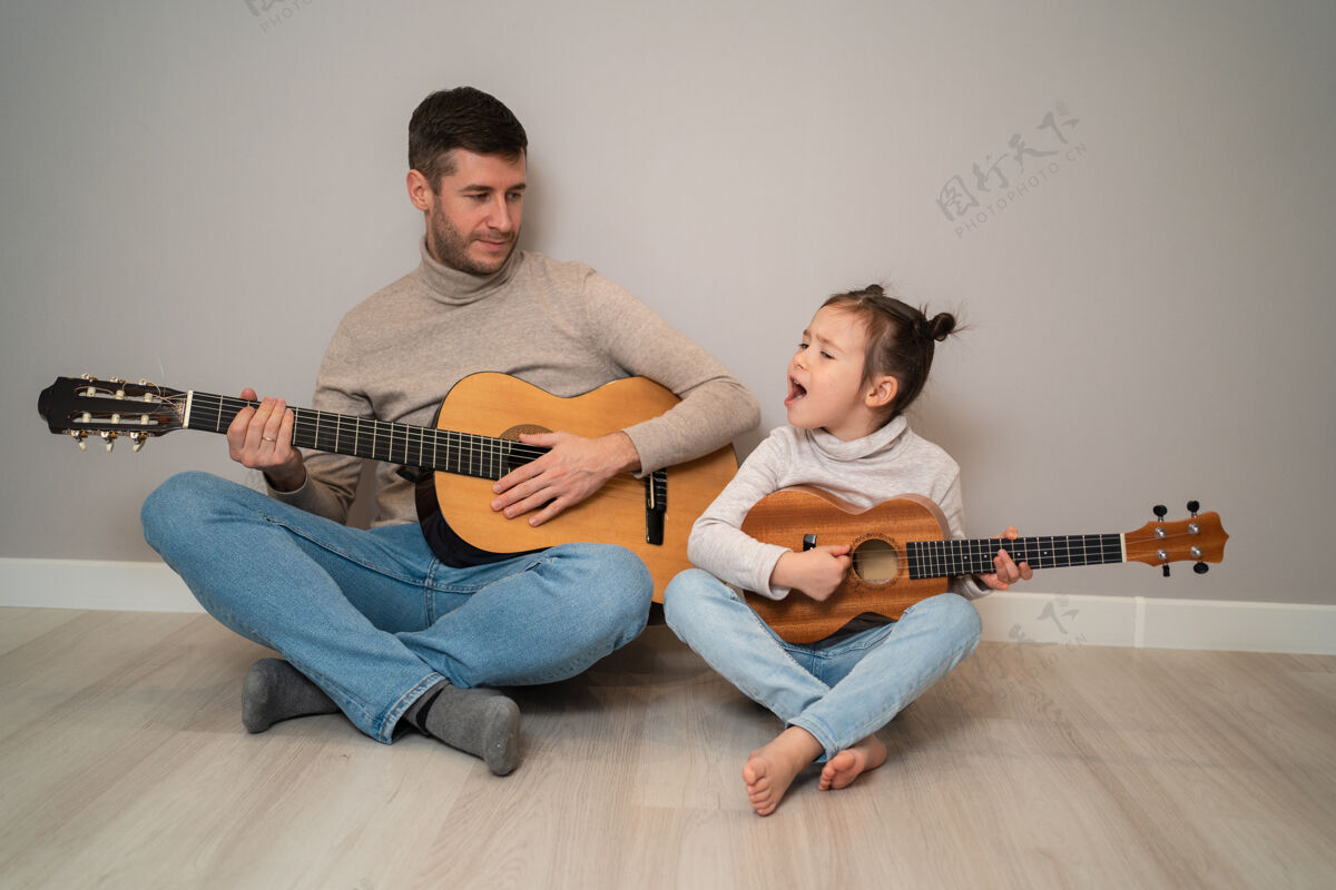 爸爸爸爸用手弹吉他女儿孩子学会用钢琴演奏乐器音乐导师父亲和孩子的二重唱可爱情感父亲