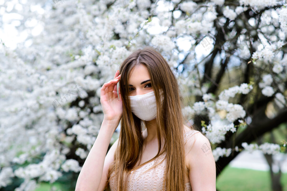 病毒在春天的花园里 一个戴着无菌医用防护口罩的年轻女子防护成人冠状病毒