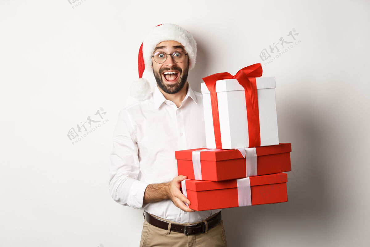 圣诞老人寒假和庆祝快乐带圣诞礼物的家伙 拿着礼物 戴着圣诞帽 站在白色的背景上胡须商人帅哥