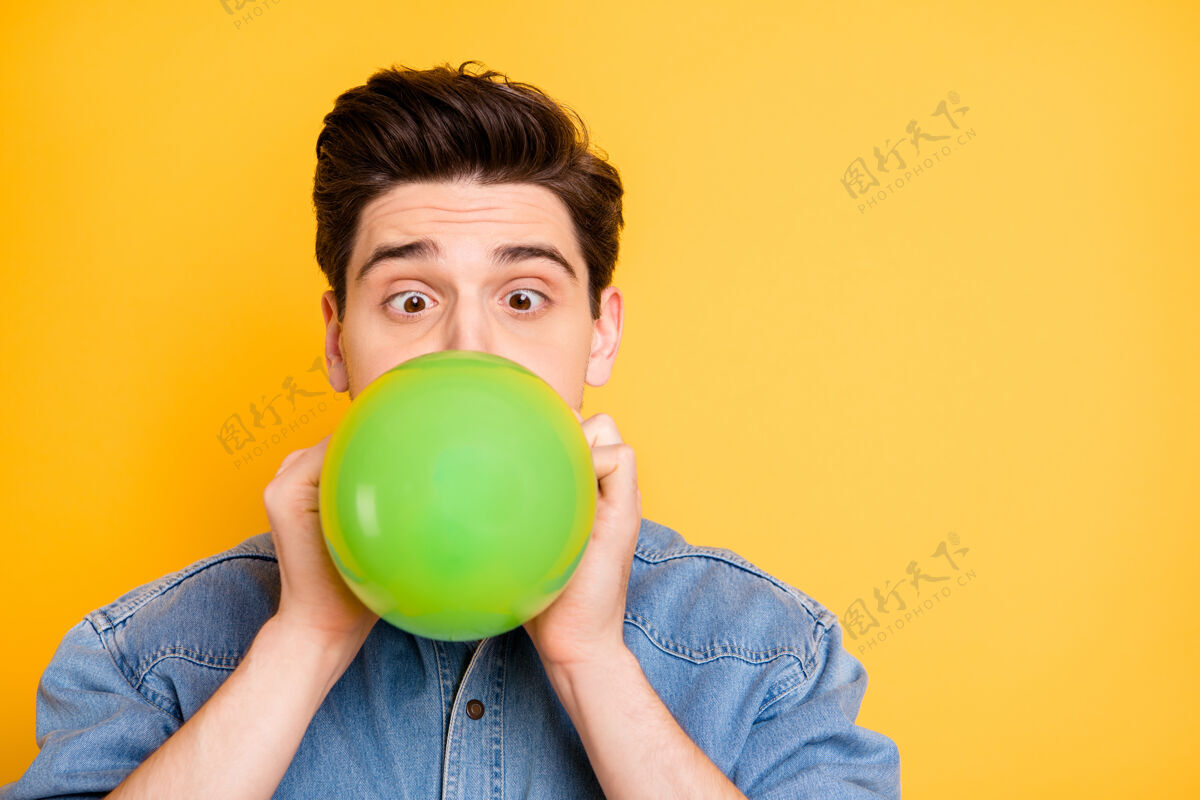 年轻特写照片滑稽可笑的男子吹他的空气球附近的空地准备即将到来的生日派对孤立的充满活力的彩色墙球吹时髦
