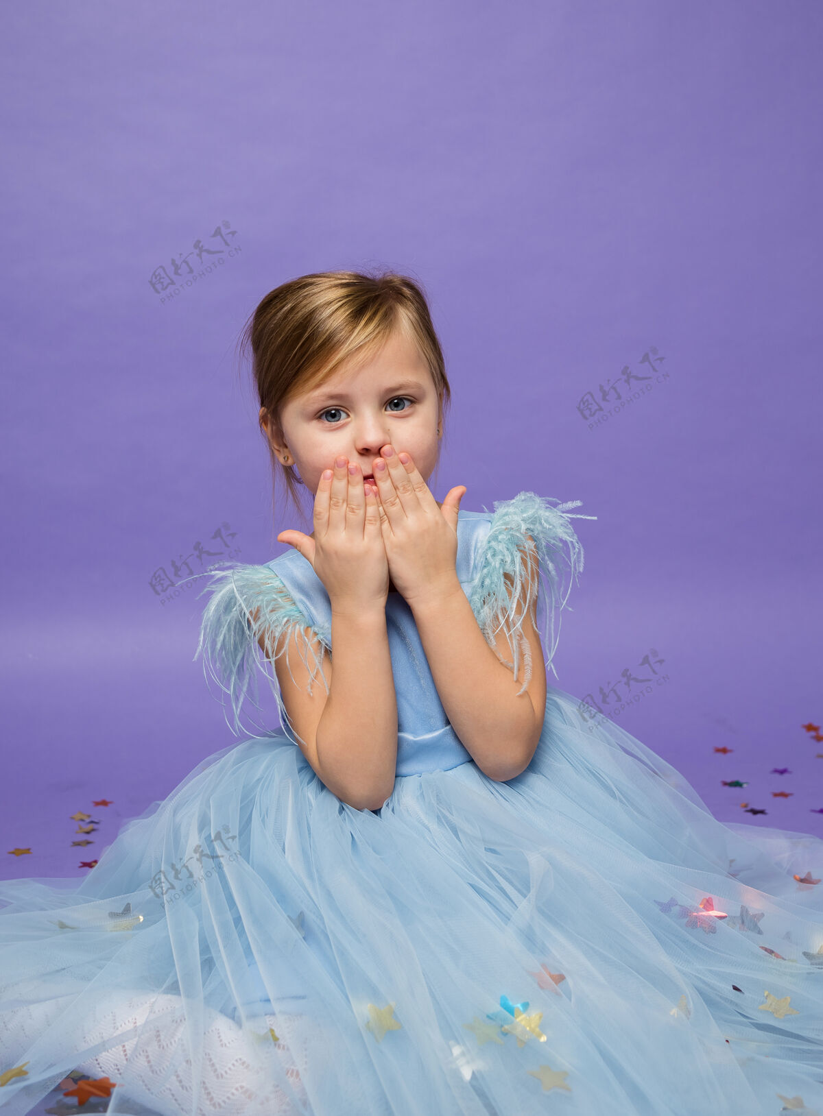 蓬松一个穿着郁郁葱葱的蓝色裙子的漂亮小女孩在紫色上吹了一个吻公主装丁香空中之吻