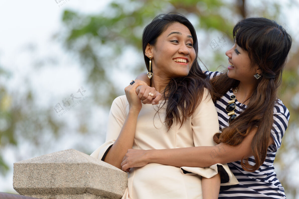 思考两位亚洲年轻女性在公园户外放松的写真自然关系放松