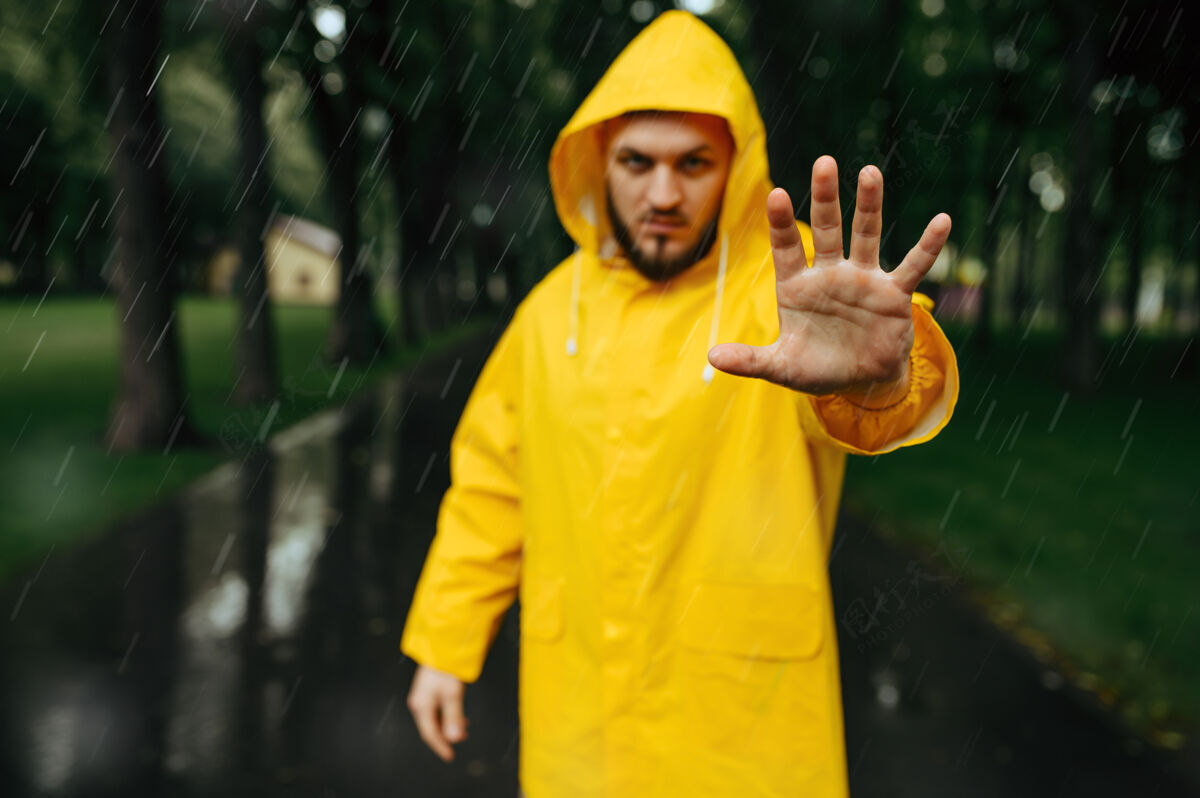 散步穿雨衣的人伸出手 夏日公园 雨天一天一个人男人穿着雨衣走在小路上 小巷里天气潮湿孤独雨滴天气
