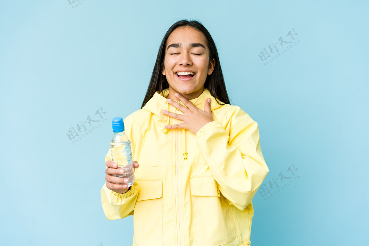快乐年轻的亚洲女人拿着一瓶水 手放在胸前大声笑了起来美丽孤立手