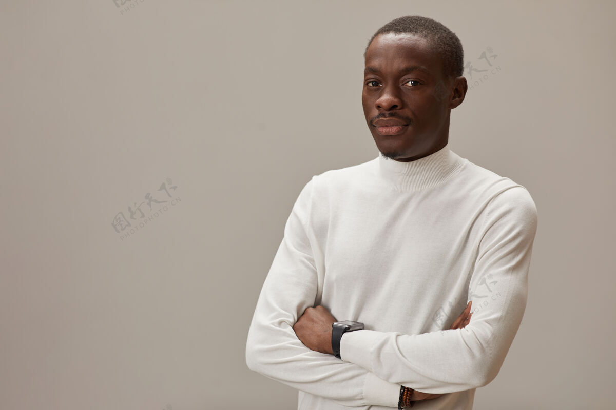 严肃一幅身穿白衬衫的年轻人双臂交叉站在灰色的墙上望着前方的画像双臂交叉自信休闲服