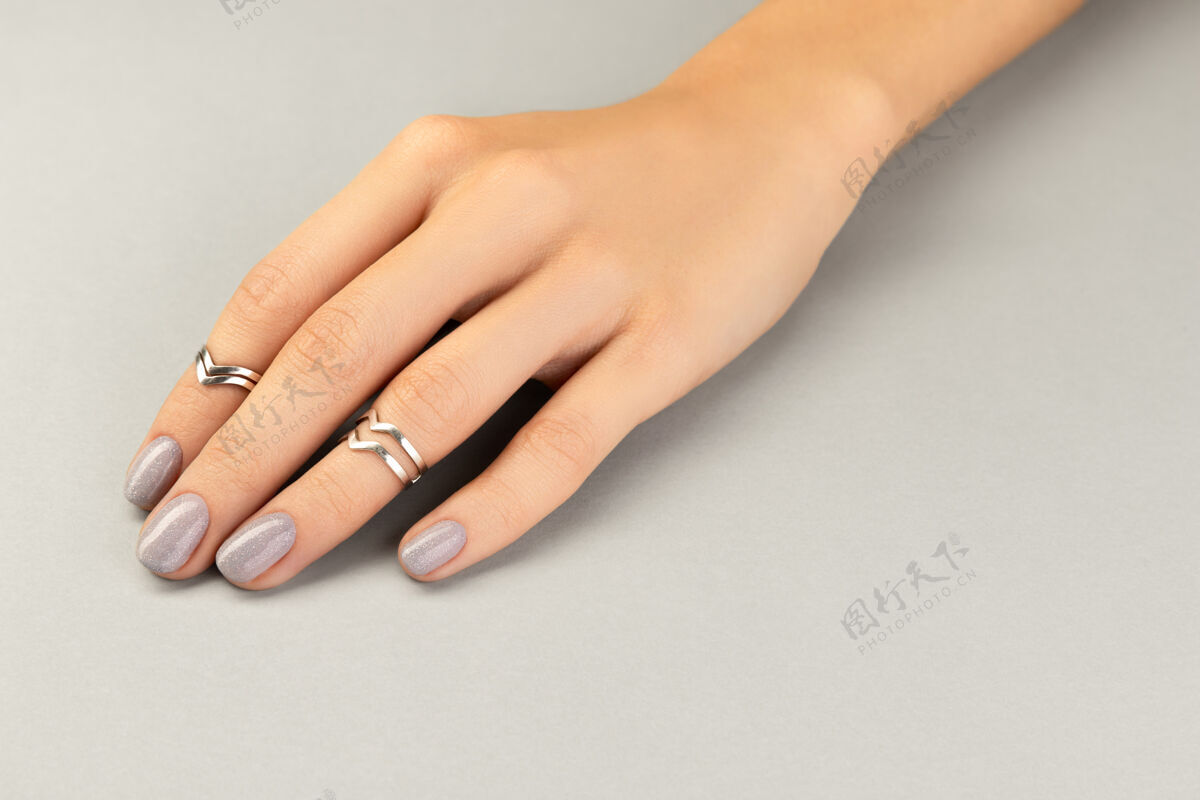 戒指漂亮整洁的女士手与最小的指甲设计在灰色健康治疗女人