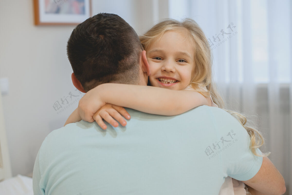 爸爸早上 美丽的小女孩在家里抱着爸爸笑着说室内拥抱惊喜