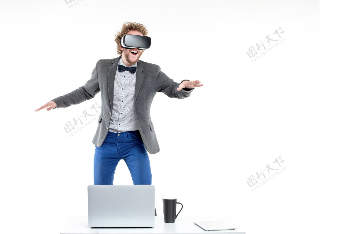 饮料一个卷发商人的画像 他站在桌子边的椅子上 手里拿着小玩意儿和一杯咖啡 戴着虚拟现实眼镜领结未来派游戏