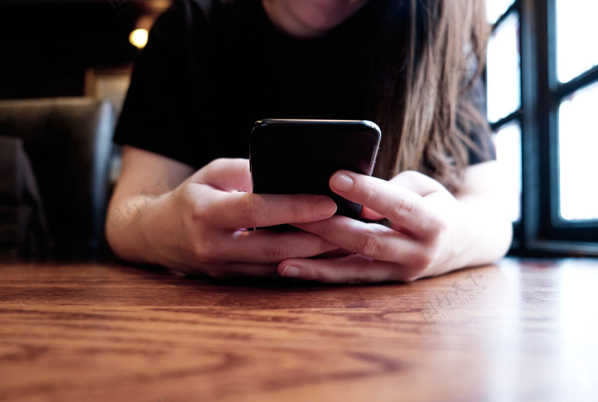 手机一位女士在餐厅用手机发短信的特写照片电话打字触摸