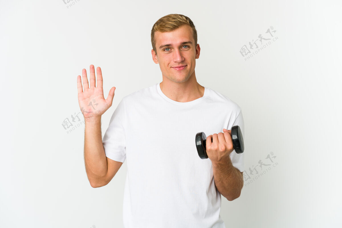 五年轻的白人男子举着一个白色的体重微笑愉快地显示数字五与手指数字健美健身