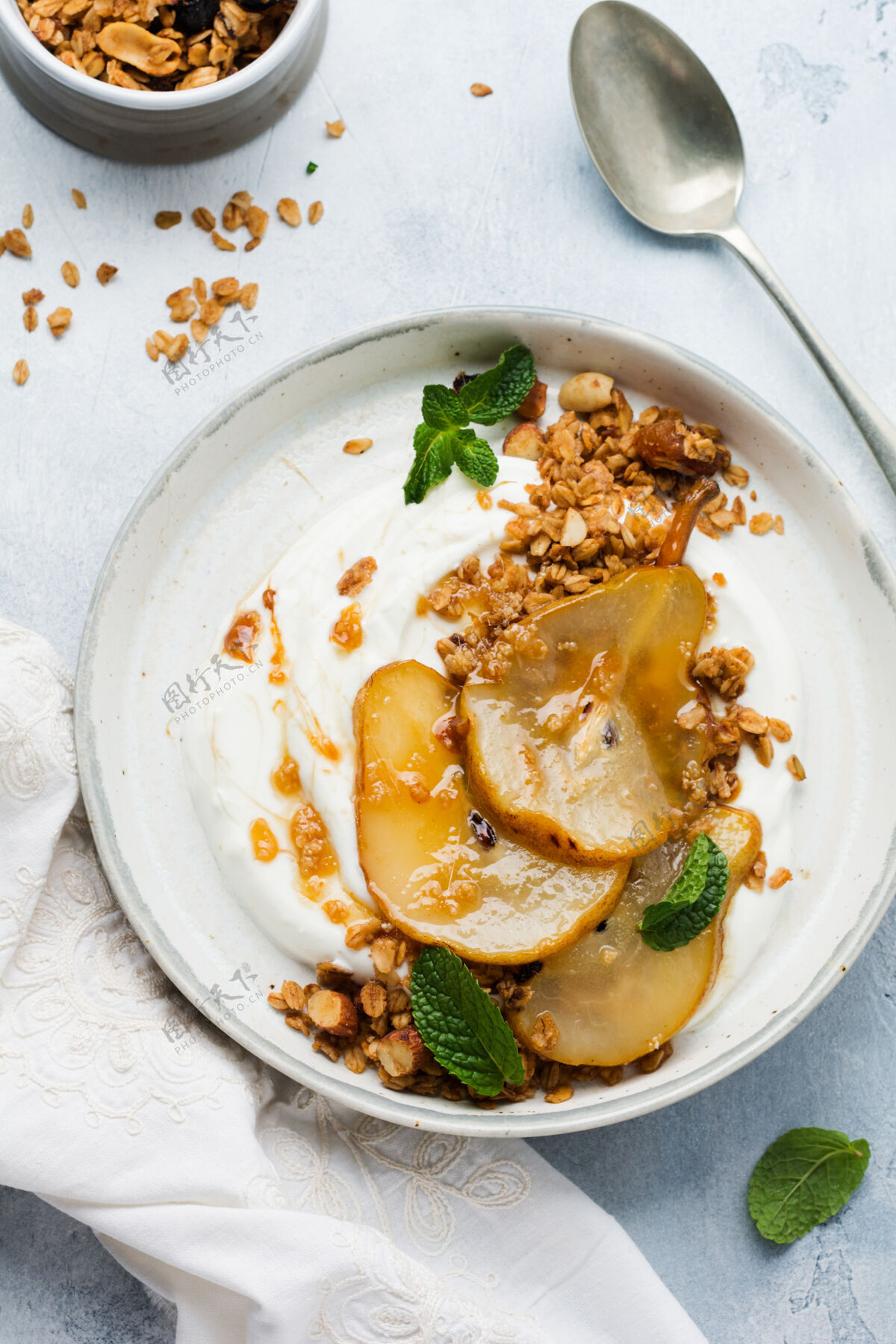 营养希腊酸奶与焦糖梨 格兰诺拉麦片 坚果和融化的糖作为一个健康的早餐灰色陶瓷盘子梨乳制品饮食