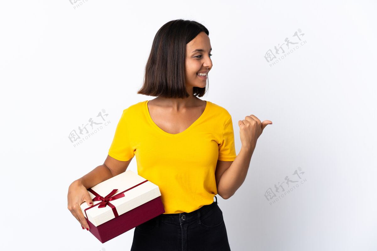 肖像年轻的拉丁女子拿着一件礼物指着白色的边上赠送一件产品年轻显示盒子