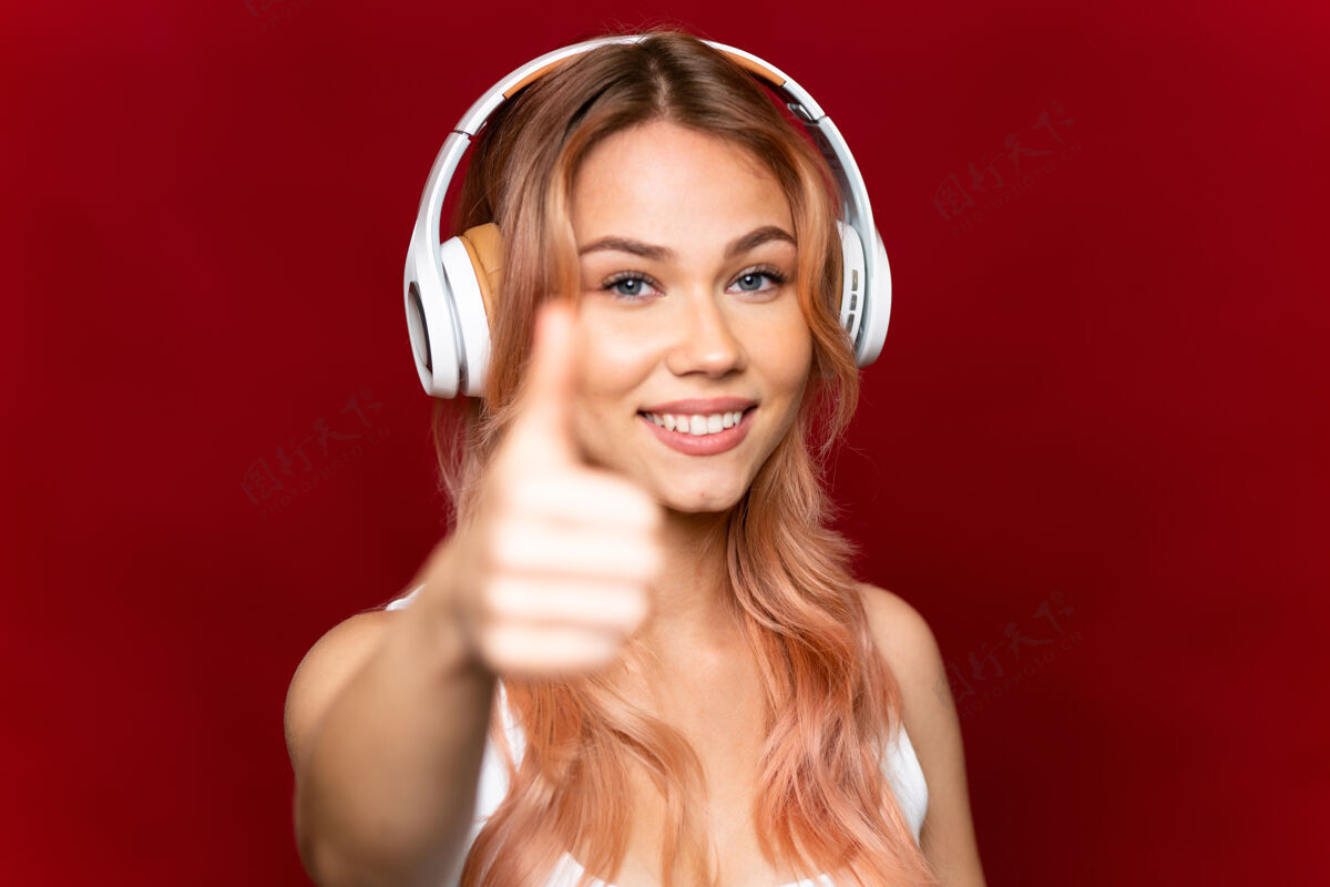 手势一个十几岁的女孩 粉红色的头发 孤立的红色 听音乐 拇指向上俄语年轻歌曲