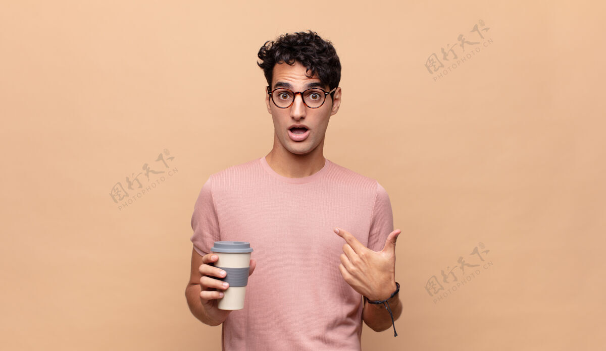 骄傲年轻帅哥拿着一杯咖啡感到高兴 惊讶和自豪咖啡馆男人兴奋