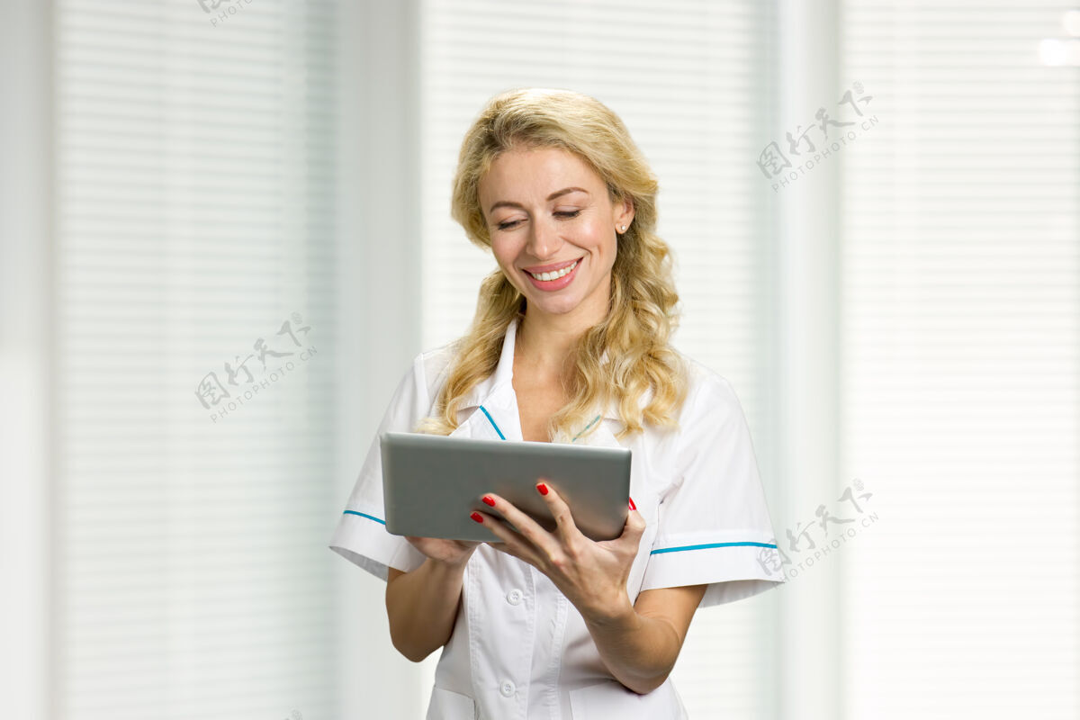 护士面带微笑的年轻护士拿着电脑兴高采烈的年轻医生看着电脑 面带微笑微笑自信肖像