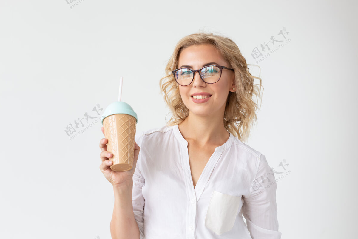 女性化穿着白衬衫的漂亮积极的年轻女孩手里拿着一杯鸡尾酒 摆出一副白人的姿势概念积极漂亮