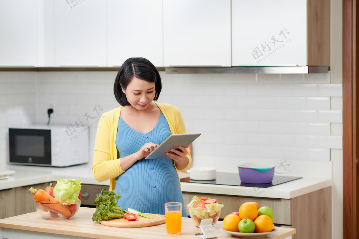 厨房孕妇拿着药片垫看清单 检查新鲜蔬菜孕妇父母美丽