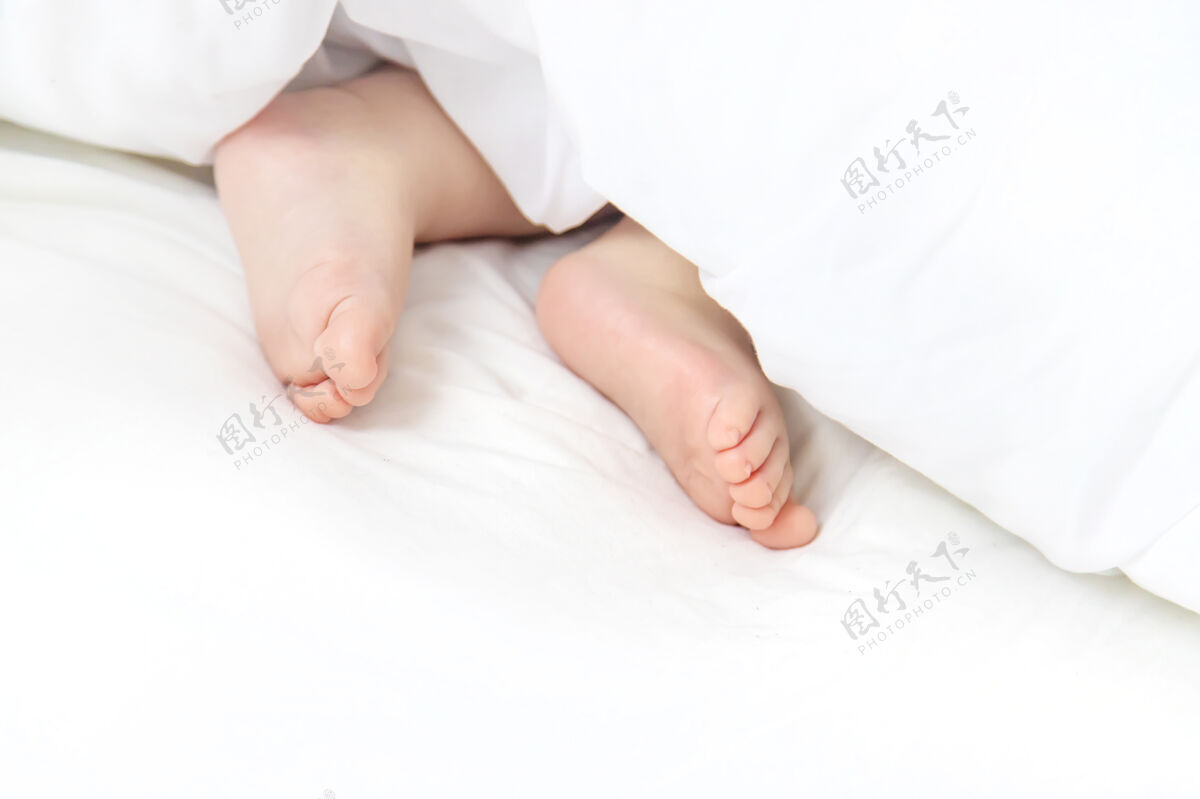 天真宝宝用脚睡在白色的床上放松腿婴儿