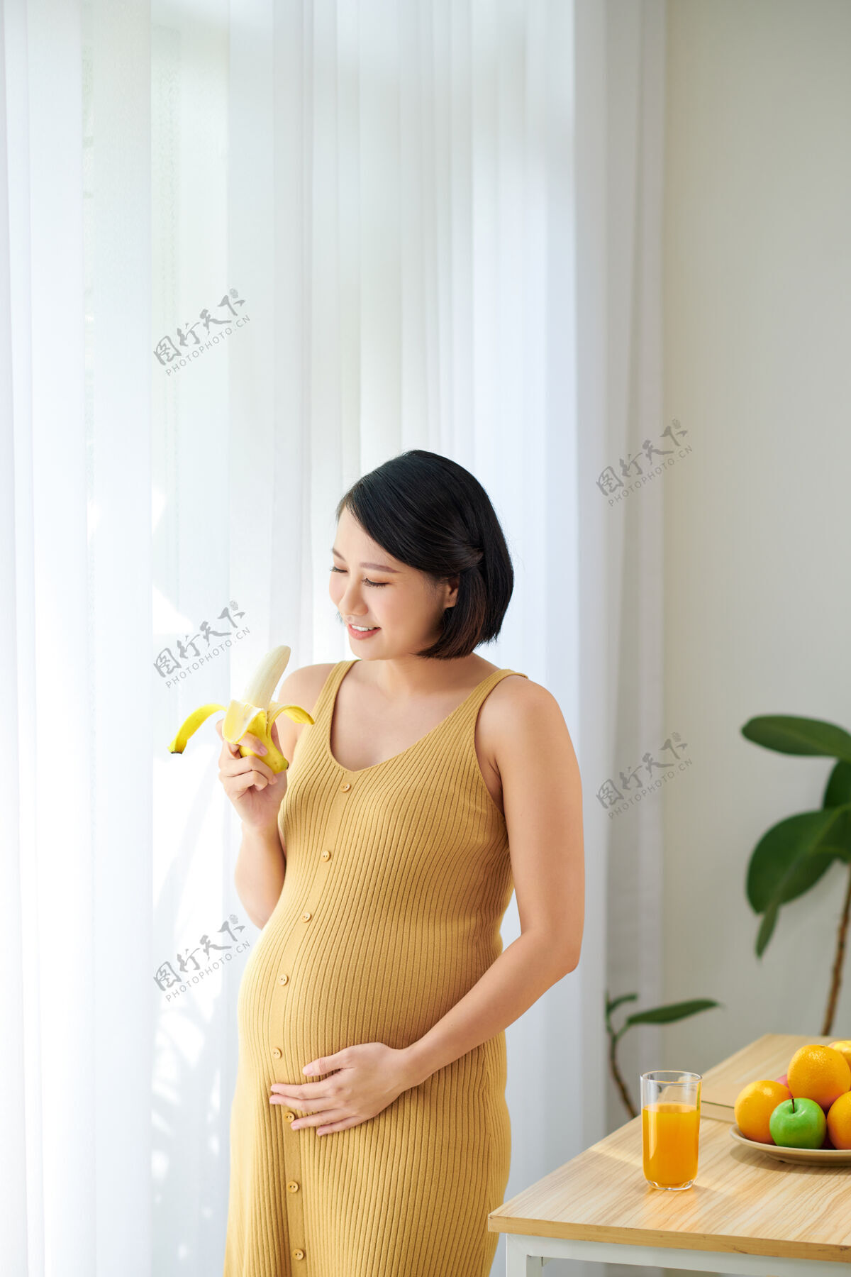 厨房孕妇在厨房做健康果汁吃香蕉早餐准备女人